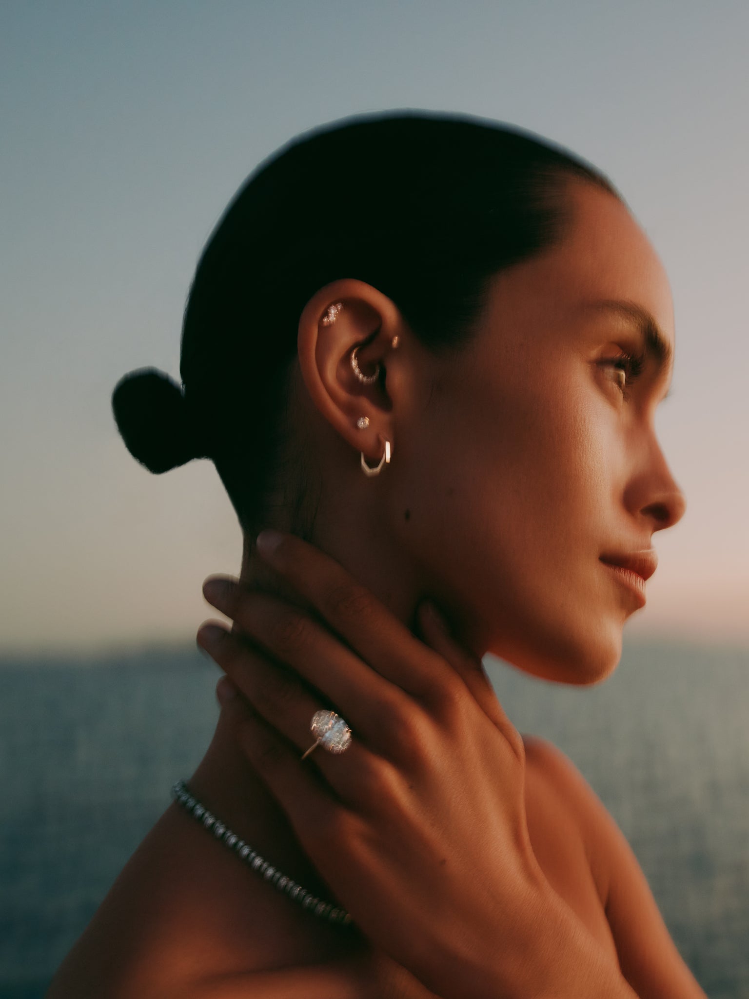 Woman wearing earrings and a ring with a scenic background