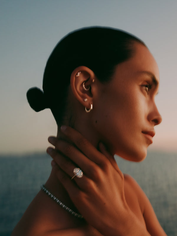 Woman wearing earrings and a ring with a scenic background